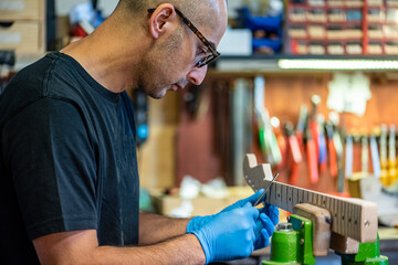 expert luthier at work on his guitar under construction, portrait of a craftsman specialized in...