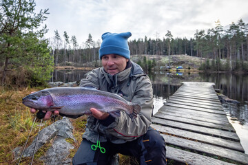 Fly fishing angler with rainbow trophy fish - 397257594
