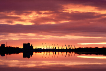 View over the Danube river on the commercial zone of port and harbor cranes at sunrise cloudy sky