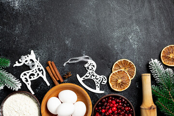 Fototapeta na wymiar Christmas baking banner with ingredients for cooking and festive decorations on black rustic background. Christmas and New Year concept.