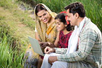 Rural family using laptop on agriculture field