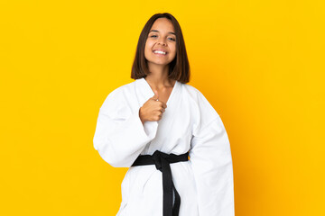 Young woman doing karate isolated on yellow background giving a thumbs up gesture © luismolinero