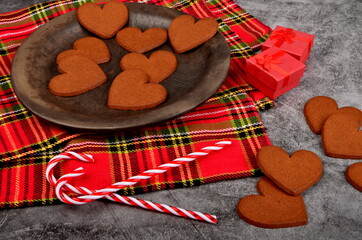 Gingerbread heart on a black clay plate and Christmas decorations .Gray concrete wall background, Gingerbread cookie and Christmas decorations. Copy space, Christmas concept