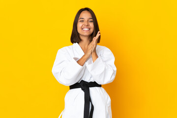 Young woman doing karate isolated on yellow background applauding after presentation in a conference © luismolinero