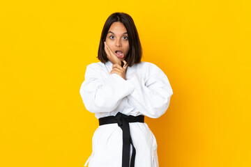 Young woman doing karate isolated on yellow background surprised and shocked while looking right