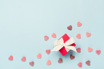 Sweet sugar candy hearts and red gift box on blue background. Valentines day concept. Flat lay, top view, copy space.