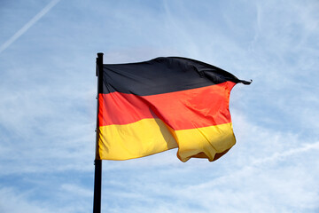 flag of the federal republic of Germany freely flutters in the wind against a blue sky, , concept of tourism, economy, politics, emigration, business