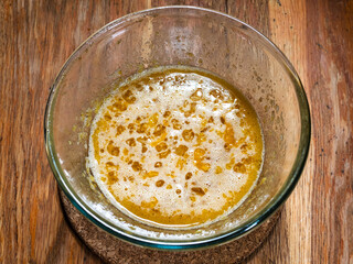 cooking sweet sponge cake at home - above view of dough ingredient of eggs, sugar and honey cooked in water bath in glass bowl on old wooden table at home kitchen