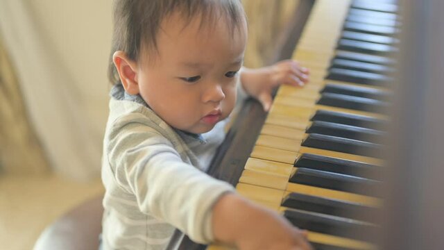 Cute little baby boy plays piano at home