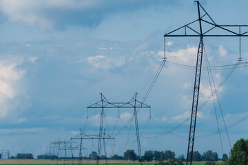 Farm field with power lines on horizon. Energy transportation