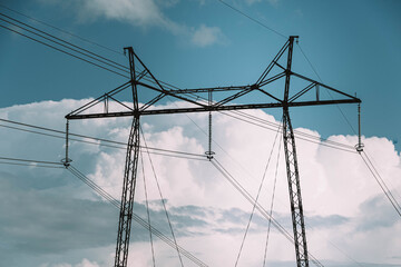 Power line tower against sky and clouds. Transmission of electricity by wire from energy company. Landscape with high voltage pylons and lines.