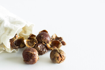 soap nuts falling out of linen bag on white background