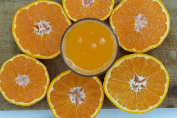 Delicious fresh squeezed tangerine juice in a transparent glass. Peeled sliced mandarin orange close up pieces.