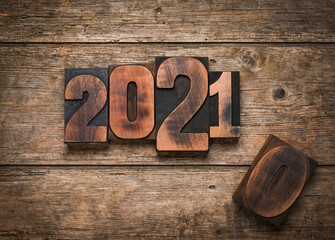 Change from year  2020 to 2021 written with vintage letterpress printing blocks on rustic wooden background