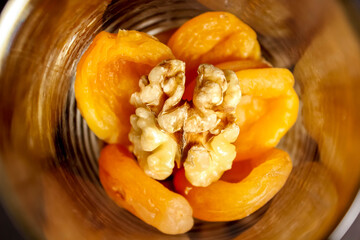 A nutritious mixture of dried apricots and walnuts in a glass Cup.