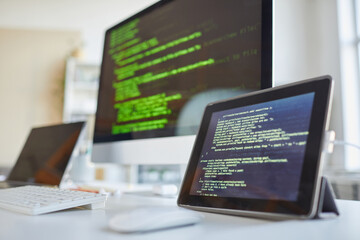 Image of digital tablet and computer monitor with software on the screens on the table at IT office