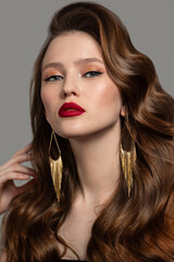 Beautiful woman with perfect makeup and hairstyle. red lips and gold earrings