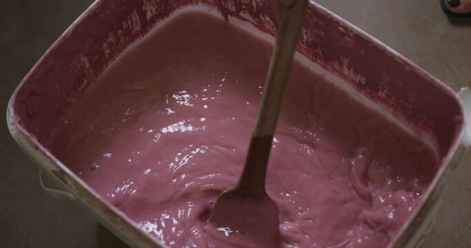Close up view of potter mixing paint in a container at pottery studio