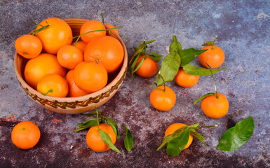 Fresh mandarin, clementine, tangerine with green leaves on a rusty surface background