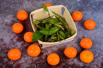 Fresh mandarin, clementine, tangerine with green leaves on a rusty surface background