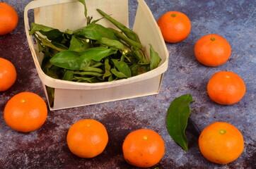 Fresh mandarin, clementine, tangerine with green leaves on a rusty surface background