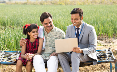 Farmer with businessman using laptop on agriculture field