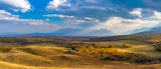 Foto op Plexiglas Uitgestrekte prairie en bos in de mooie herfst. Zonlicht passeren blauwe lucht en wolken op bergen. Herfst kleur landschap achtergrond. Waterton Scenic Spot, Waterton Lakes National Park, Alberta, Canada. © Shawn.ccf