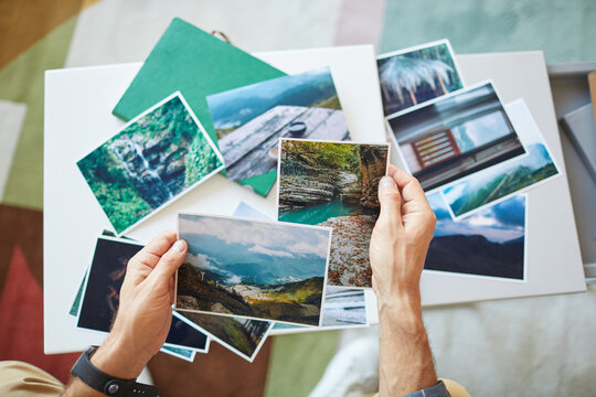 Close-up of man choosing the photos for collage or making a map of desires at the table