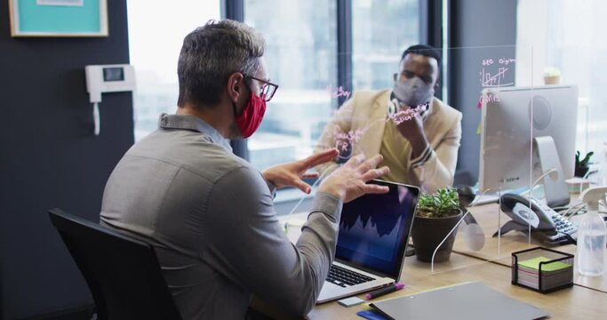 Diverse male office colleagues wearing face masks discussing at modern office