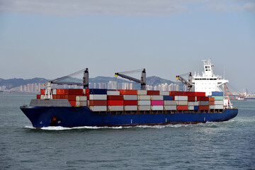 Fully loaded, geared container ship departing port of Xiamen, China. 