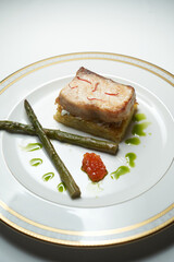 Baked Sturgeon fish fillet and asparagus on a white plate