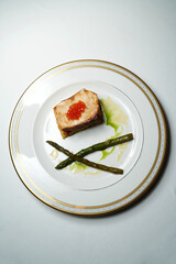 Baked Sturgeon fish fillet and asparagus on a white plate