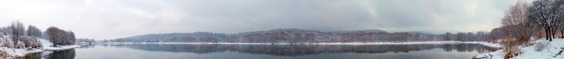 Panorama of winter lake with fog and forest