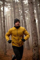 Young man running in autumn forest and exercising for trail run marathon endurance race