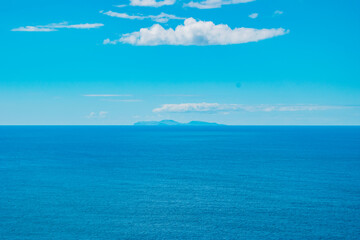Obraz premium Turquoise Atlantic Ocean with silhouette of São Jorge island on the horizon and clouds, gradient colors - Azores PORTUGAL