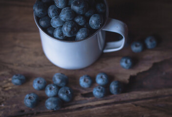 Blueberries in vintage tin cup on rustic wood background