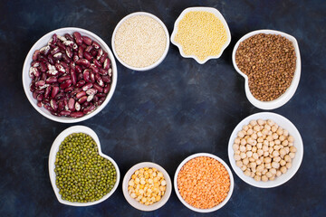 Variety of cereals and legumes on a dark background. Lentils, red beans, quinoa, chickpeas, mash, split peas, millet, buckwheat. Gluten-free products. Top view, copy space.