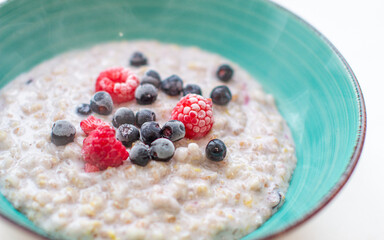 Oatmeal porridge in a plate with currant and raspberry berries. 