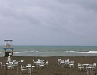 vista malinconica di tavolini sulla spiaggia al mare in inverno