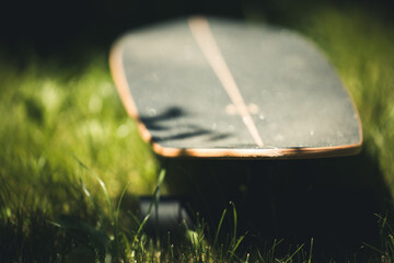 skateboard on green grass from above © Cavan