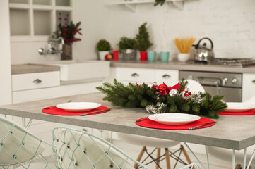 New Year's decor of modern kitchen in Scandinavian style. Serving a white plate on a red rustic napkin with a close-up and copy space. Hygge kitchen details New year concept. Selective focus