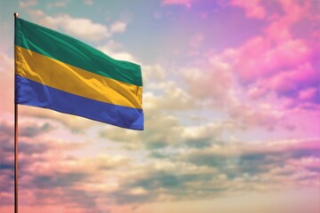 Fluttering Gabon flag mockup with the space for your content on colorful cloudy sky background.