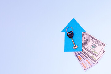 The key to a new apartment or house lies on a small blue paper house on a fan of 100 dollar bills