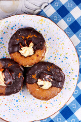 Top view of three chocolate covered marshmallow on plate and blue napkin in a white square background