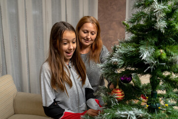 Mother and daughter assembling the Christmas tree in their living room. Selective focus