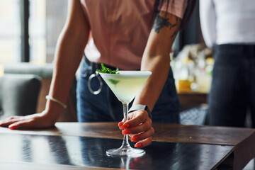 Waiter's hand. Green mint and yellow lime. Close up view of fresh summer cocktail on the wooden table