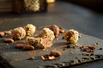 Handmade chocolates sprinkled with pistachio crumbs on a graphite board photographed in close-up