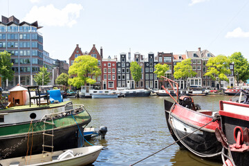 Obraz premium View of Amstel River in the city center of Amsterdam. Seen from Roeterseiland with canal houses, canal boats, Schutssluis.