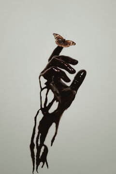 Ecological catastrophe concept consisting of crop hand of human smeared with petroleum holding butterfly on finger