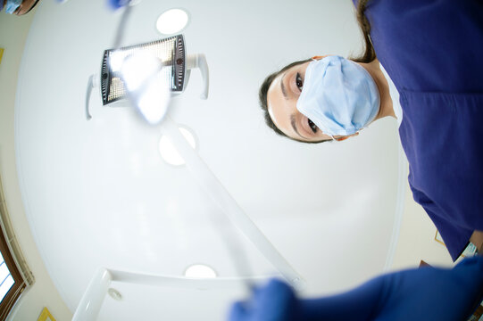 From below female Asian dentist holding mirror while working in modern office in clinic
